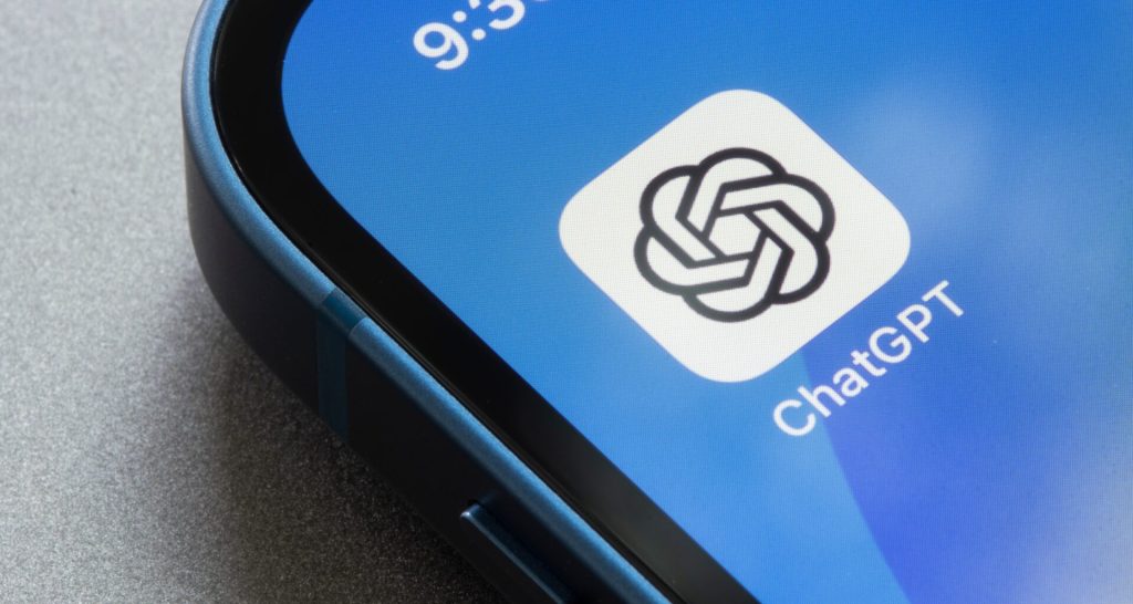 A tela de um smartphone azul mostra o ícone do aplicativo ChatGPT, com seu logotipo preto e o texto "ChatGPT", em um fundo azul.