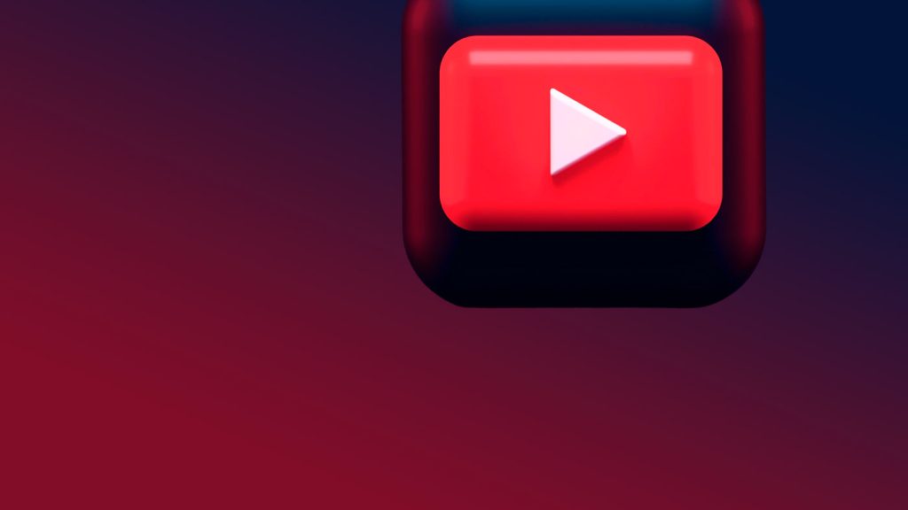Um ícone 3D do botão de play do YouTube, vermelho com um triângulo branco, sobre um fundo gradiente que transita de azul escuro para vermelho.